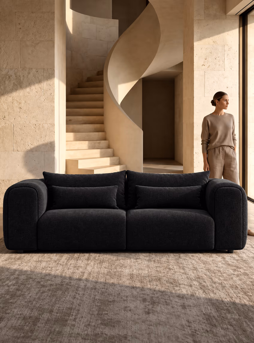 The charcoal Luma sofa in a stone hallway beside a spiral staircase