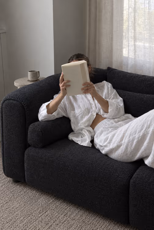 Emma leaning back on a charcoal Luma sofa