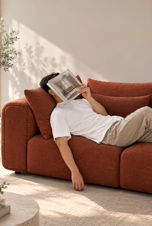 Oliver stretched out on a terracotta Luma sofa, a magazine over his face
